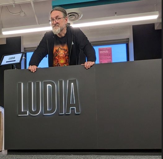 Man standing behind a reception desk marked "Ludia"